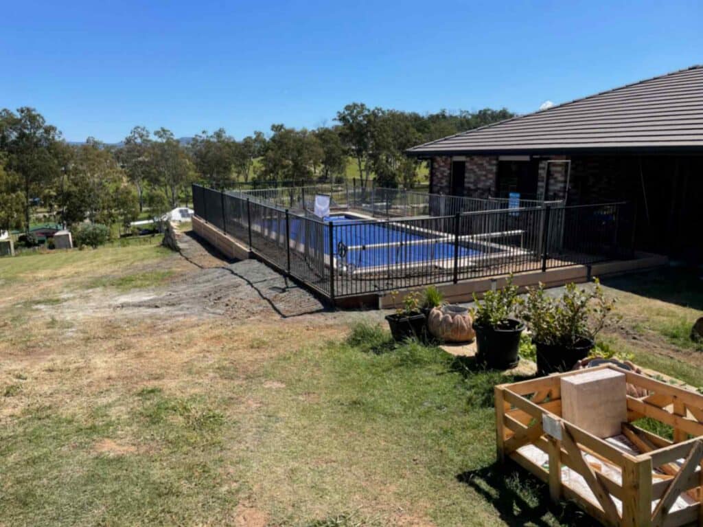 Black steel pool fence enclosing a paved outdoor pool area, an example of quality fencing Toowoomba homeowners choose for pool safety and style.